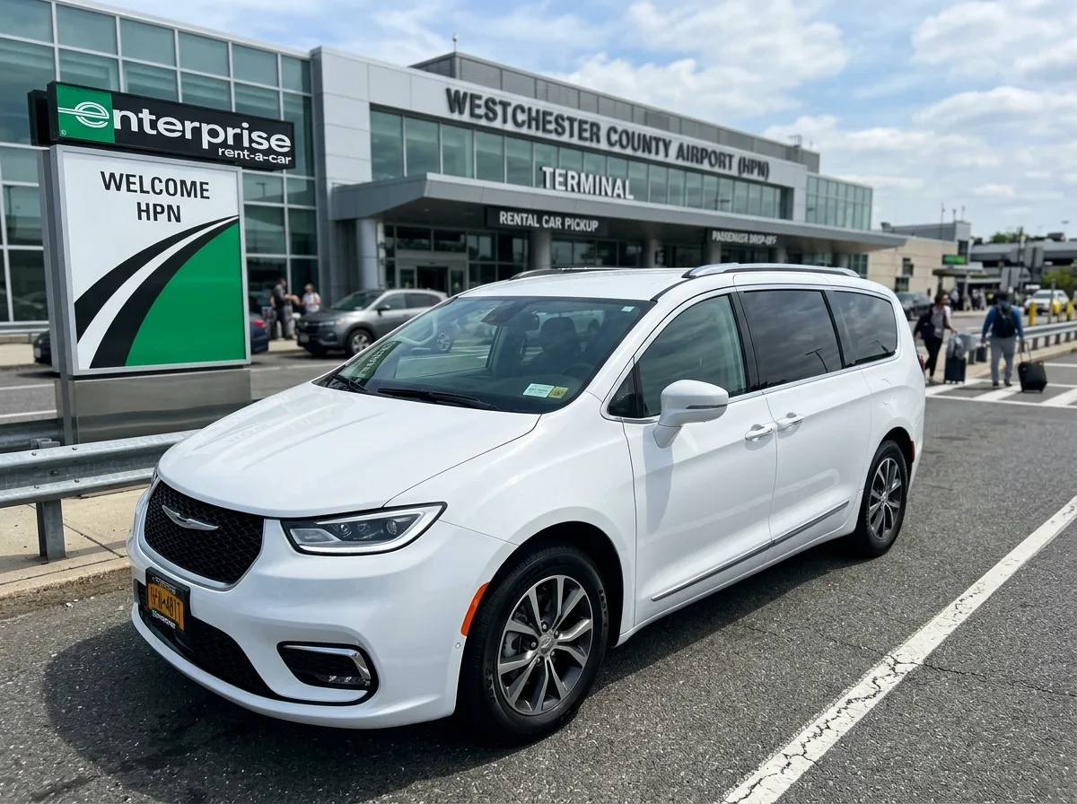 Chrysler Pacifica minivan rental at Westchester airport, white, family vehicle, three-quarter front view, bright white studio